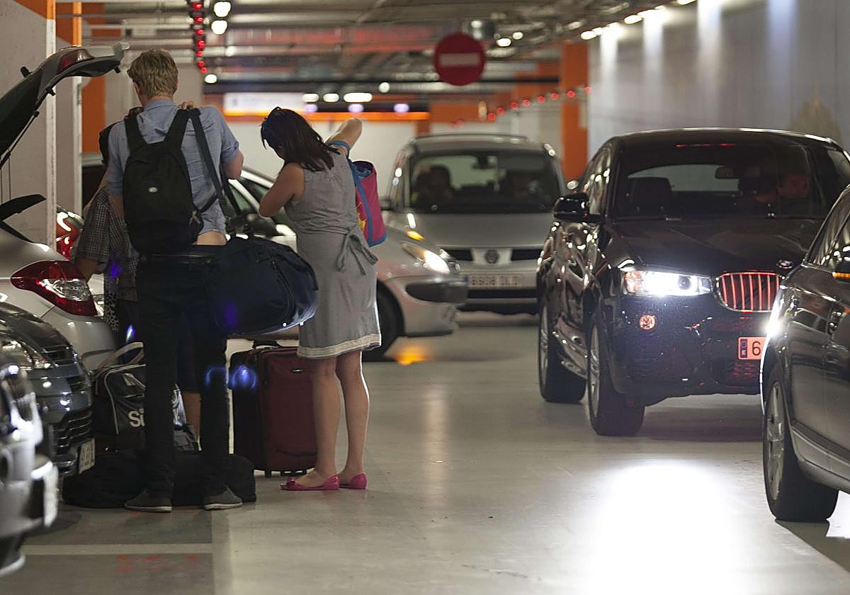 Unos turistas sacan sus maletas de un vehículo en el parking de La Concha.