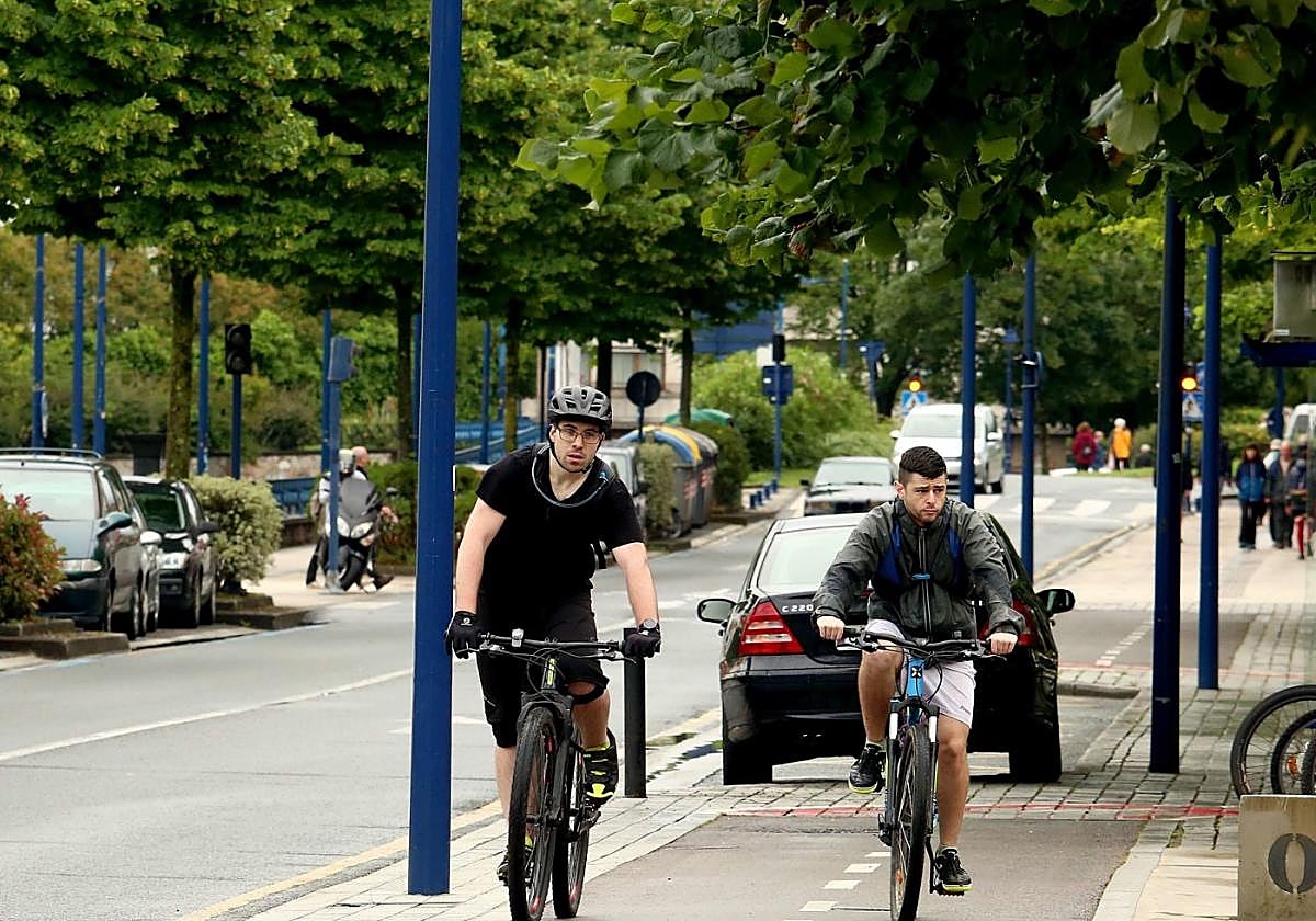 Dos jóvenes circulan en bicicleta por las cercanías del río Oiartzun.