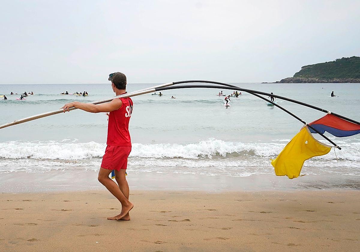 Una socorrista portada varias banderas en la playa de la Zurriola en San Sebastián.