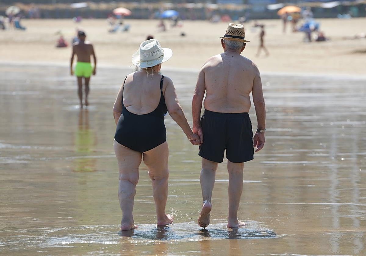 Dos pensionistas pasean por la playa de Deba.