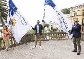 Edurne Egaña (EKP), el alcalde Eneko Goia y José Miguel Ayerza (ADEGI) con las dos Banderas de La Concha que se entregarán a los ganadores el próximo día 14 de septiembre.