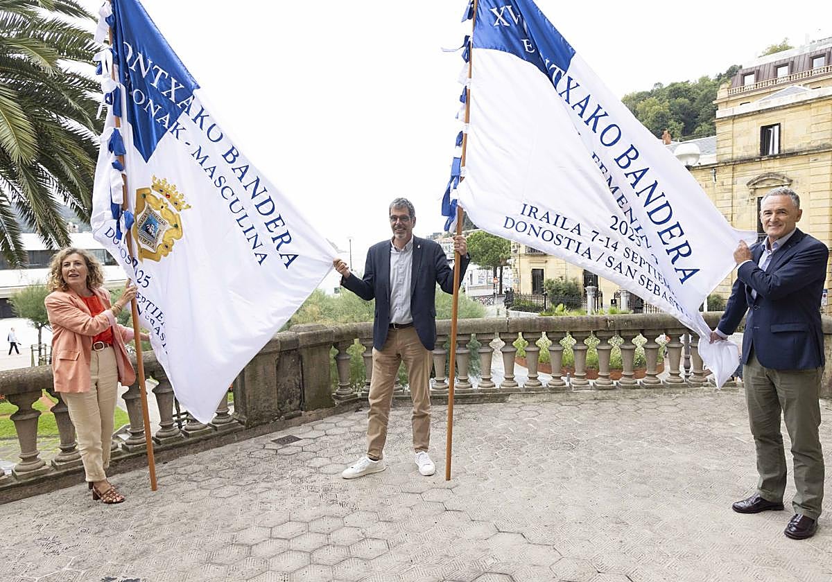 Edurne Egaña (EKP), el alcalde Eneko Goia y José Miguel Ayerza (ADEGI) con las dos Banderas de La Concha que se entregarán a los ganadores el próximo día 14 de septiembre.