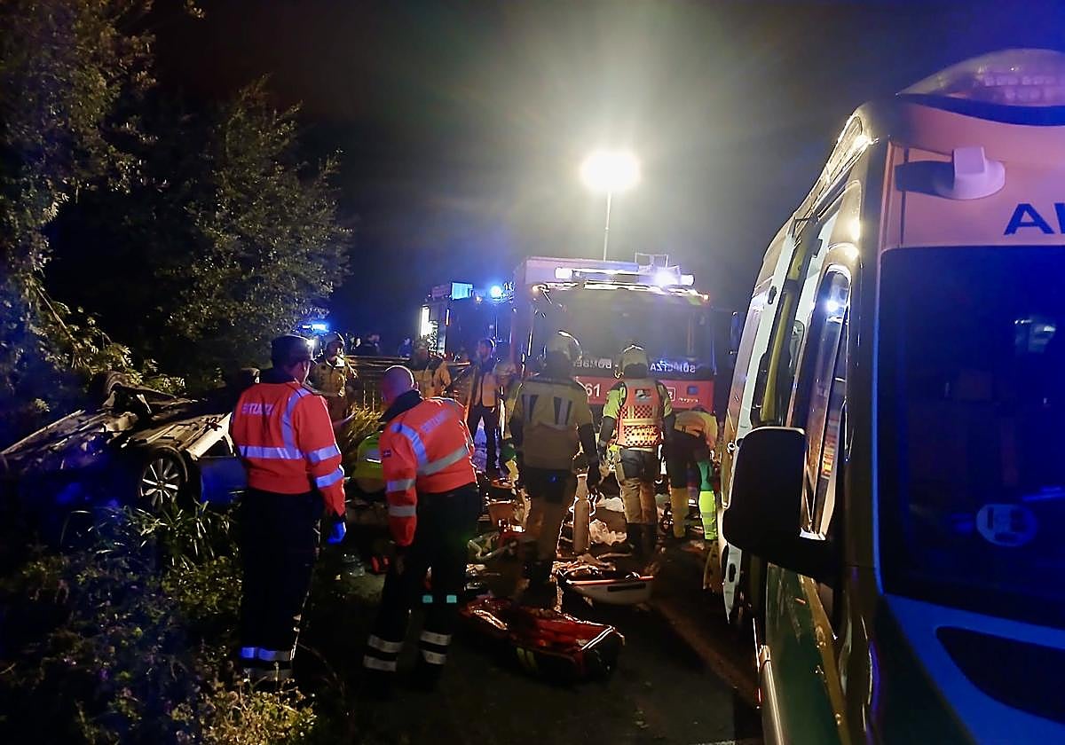 Los servicios de emergencia, junto al vehículo accidentado, que quedó volcado