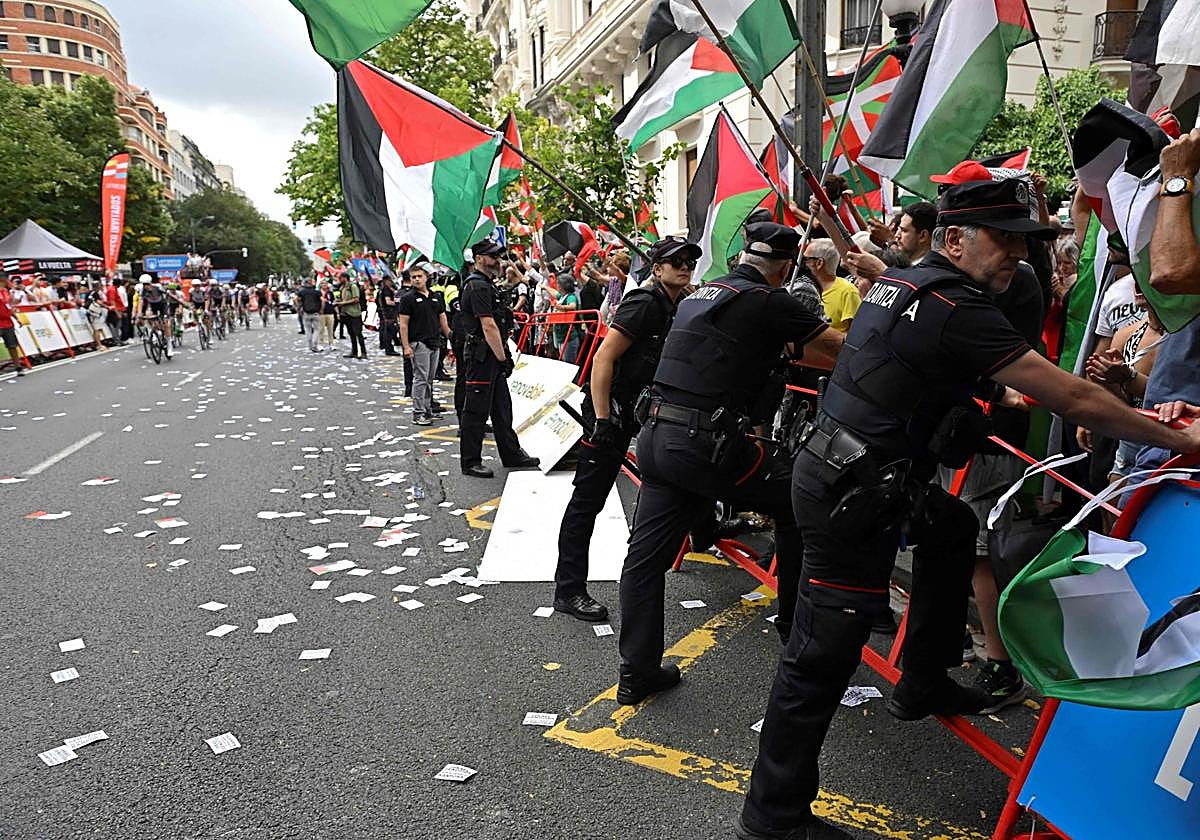 Ertzainas sujetan la valla tras la invasión de la protesta en favor de Palestina en la llegada de La Vuelta a Bilbao.