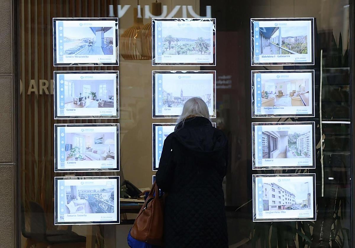 Un mujer observan los pisos a la venta en una inmobiliaria