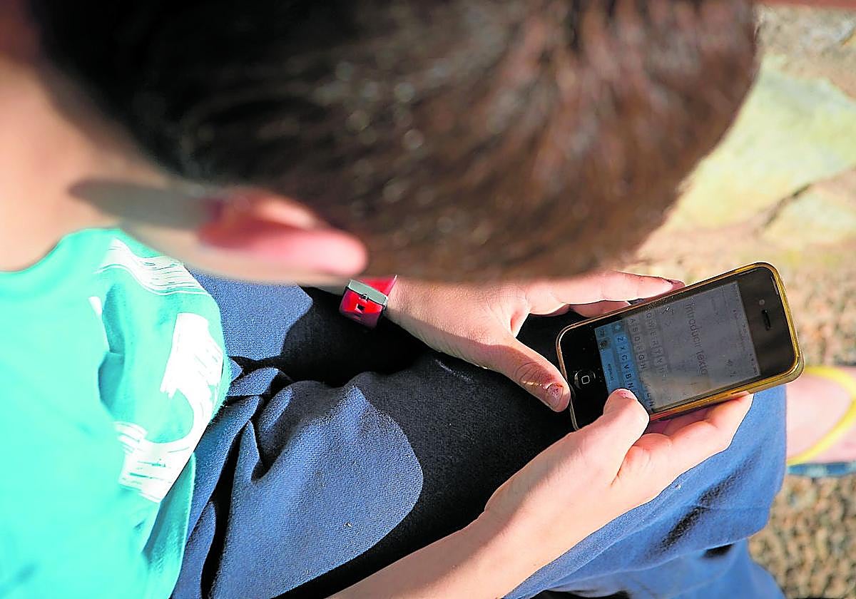 Un menor de 14 años consulta su teléfono móvil, que a veces se convierte en una herramienta para cometer delitos.