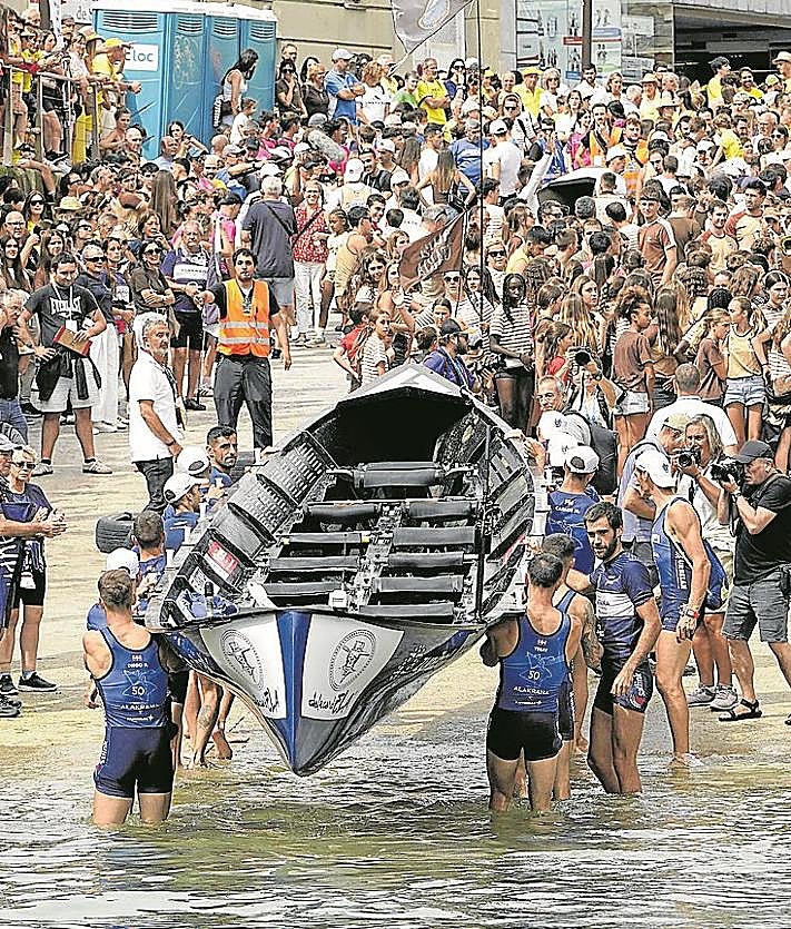 Imagen secundaria 2 - Arriba, aficionadas de San Juan animan a los suyos desde un barco en la bahía. Debajo, los remeros de Urdaibai se abren paso en la rampa del muelle. Y aficionados de Getaria animan a los suyos en el Muelle.