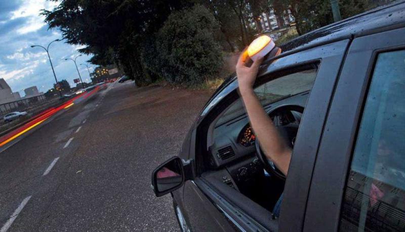 Un conductor coloca una baliza V16 en la parte superior del vehículo.