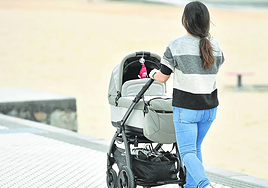 Una madre pasea a su bebé en un carrito junto a la playa de Ondarreta.