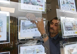 Zigor Aginagalde, de la inmobiliaria Bibai de Arrasate, se dispone a retirar un anuncio del escaparate.