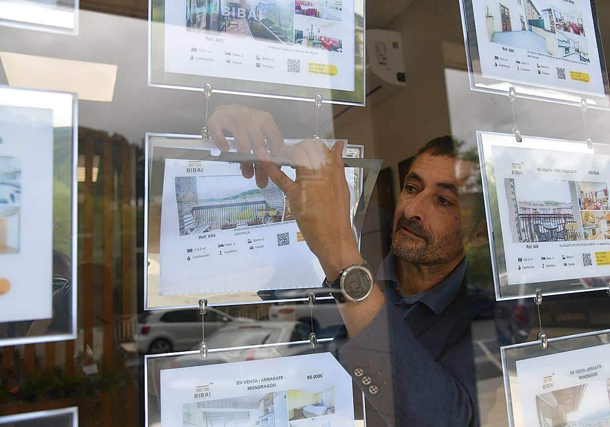 Zigor Aginagalde, de la inmobiliaria Bibai de Arrasate, se dispone a retirar un anuncio del escaparate.