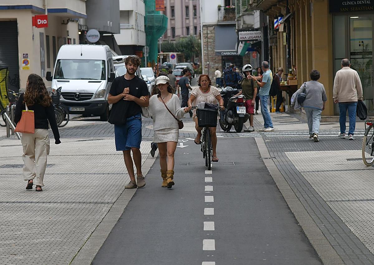 Imagen secundaria 1 - Utilizar el móvil y llevar auriculares está prohibido. Debajo, peatones invadiendo el bidegorri y un elemento obligatorio de la bicicleta, el timbre.