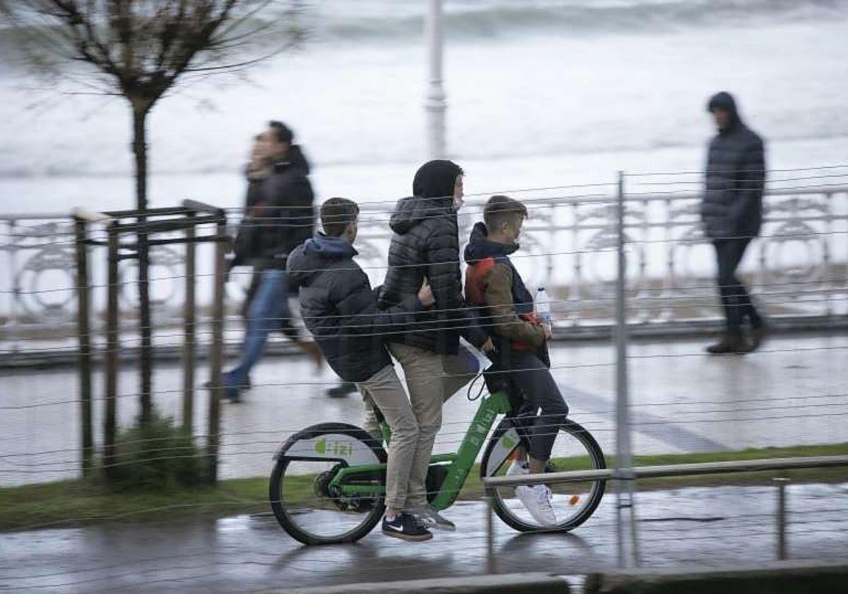 Tres chicos en una bicicleta junto a la playa de La Concha en una imagen de archivo.