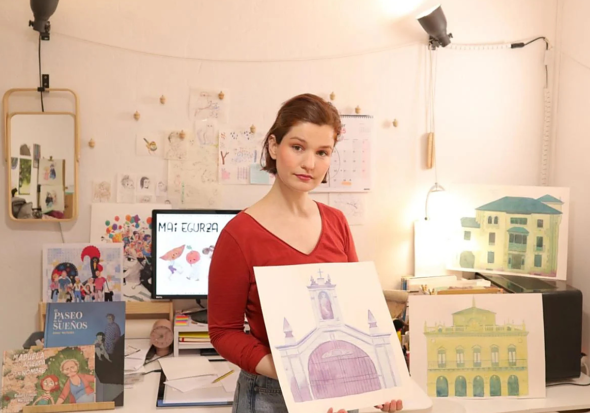Rodeada de algunas de sus obras y con las acuarelas originales que componene uno de los carteles de Irun.