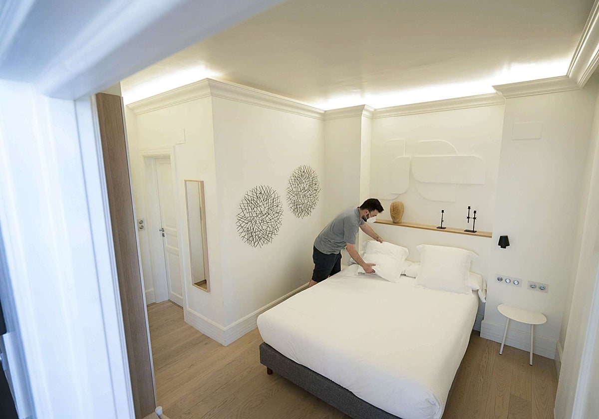 Un empleado de un piso turístico legal de Donostia prepara una habitación.