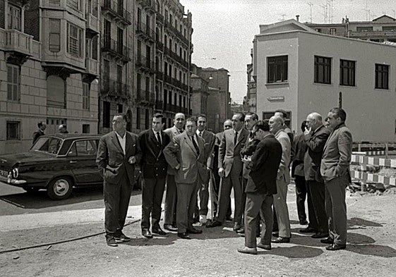 Delante, unas autoridades visitando obras. Detrás, el cine Miramar.