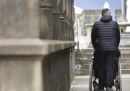 Imagen de una persona paseando con un familiar en silla de ruedas.