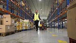 Recogida. Un voluntario transporta un carro, mientras se ven las estanterías vacías de fondo.