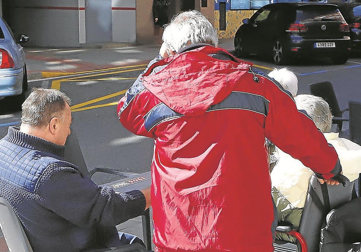 Una persona cuida a un mayor en silla de ruedas.