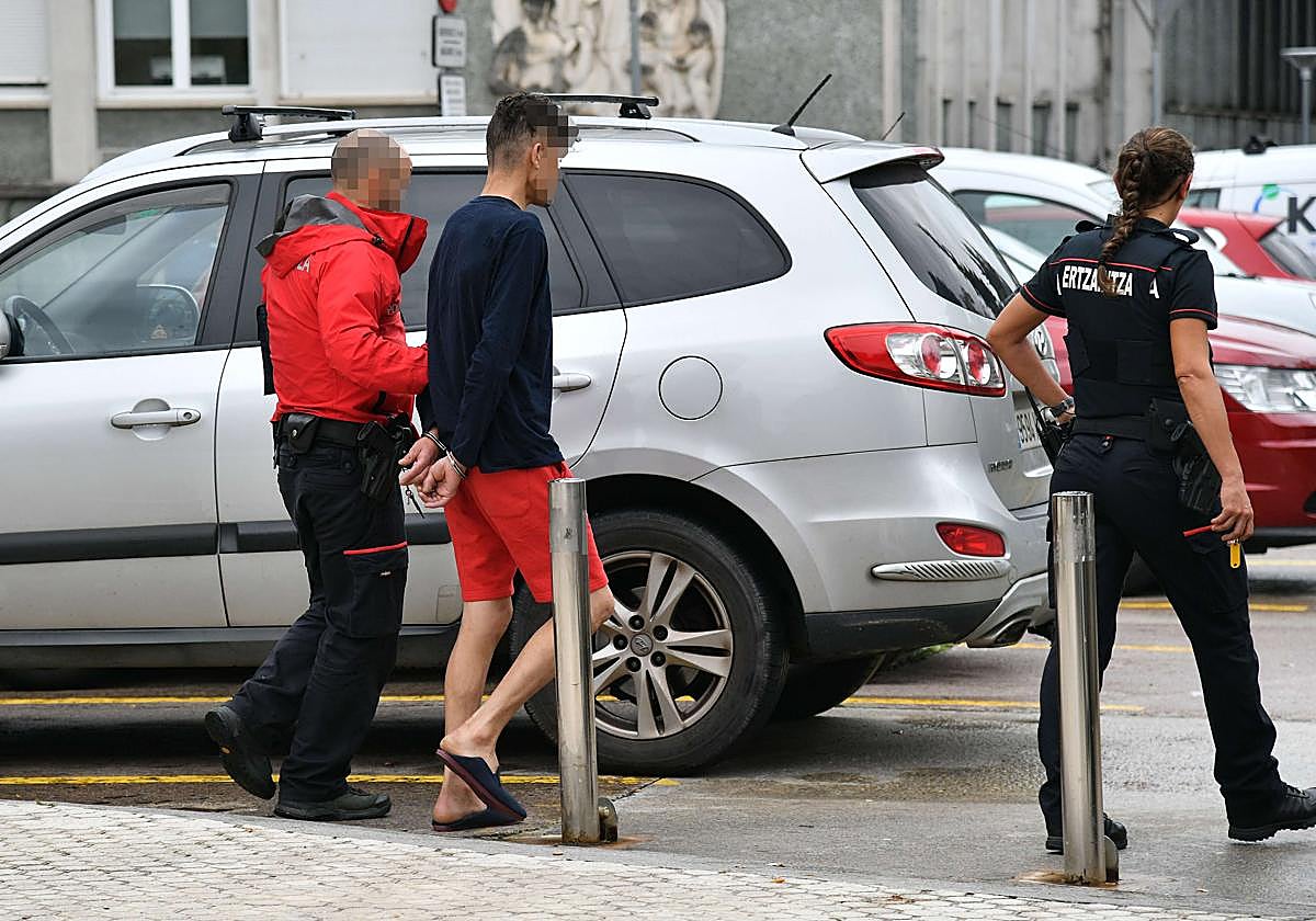 Dos ertzainas trasladan a un detenido en las inmediaciones del Hospital Donostia.
