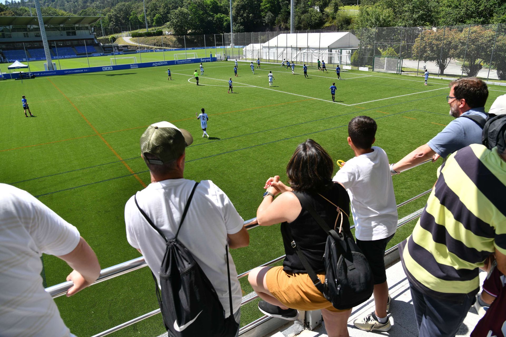 Padres presenciando un partido de fútbol base.