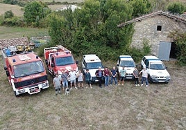 Algunos de los voluntarios que partirán el lunes a África posan con parte de los vehiculos que llevarán