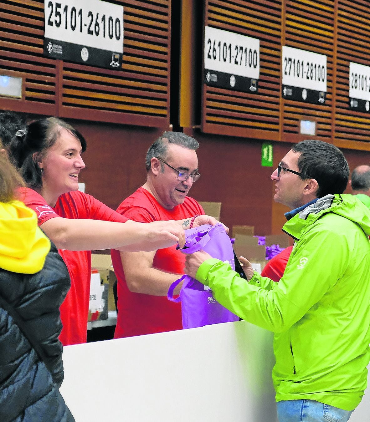 Una voluntaria del Fortuna entrega el dorsal a un participante en la carrera en la feria del Kursaal.