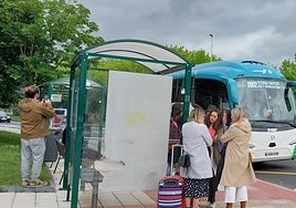 Viajeros esperando al autobús en la marquesina.