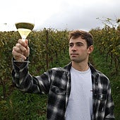 Unai Arrieta levanta una copa de vino Zuka en medio de un viñedo.