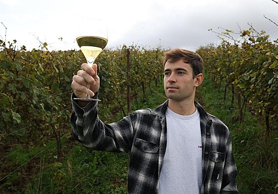 Unai Arrieta levanta una copa de vino Zuka en medio de un viñedo.
