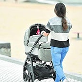 Una madre pasea a su bebé en un carrito junto a la playa de Ondarreta.