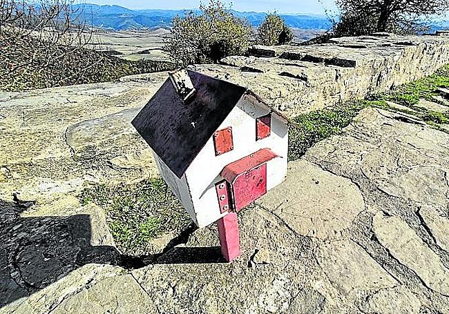 Buzón con forma de casa, rodeado de los muros del castillo, en la cima de Irulegi.