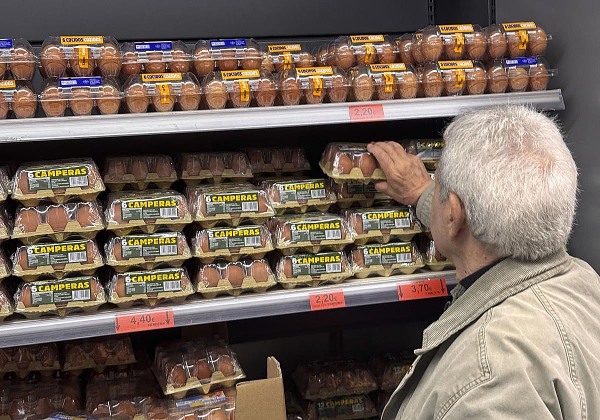 Un señor decide qué huevos comprar en un supermercado.
