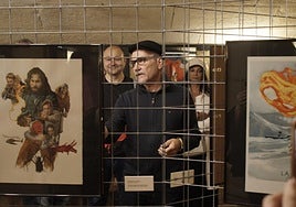 Fernando entre sus obras en la inauguración de su exposición. De fondo, dos fans del horror.