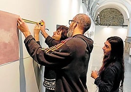 Tres de los 4 artistas participantes en la exposición durante el montaje de la muestra este martes por la tarde en los claustros de Kulturate.