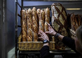 Una panadera sostiene diferentes barras en su comercio de París.