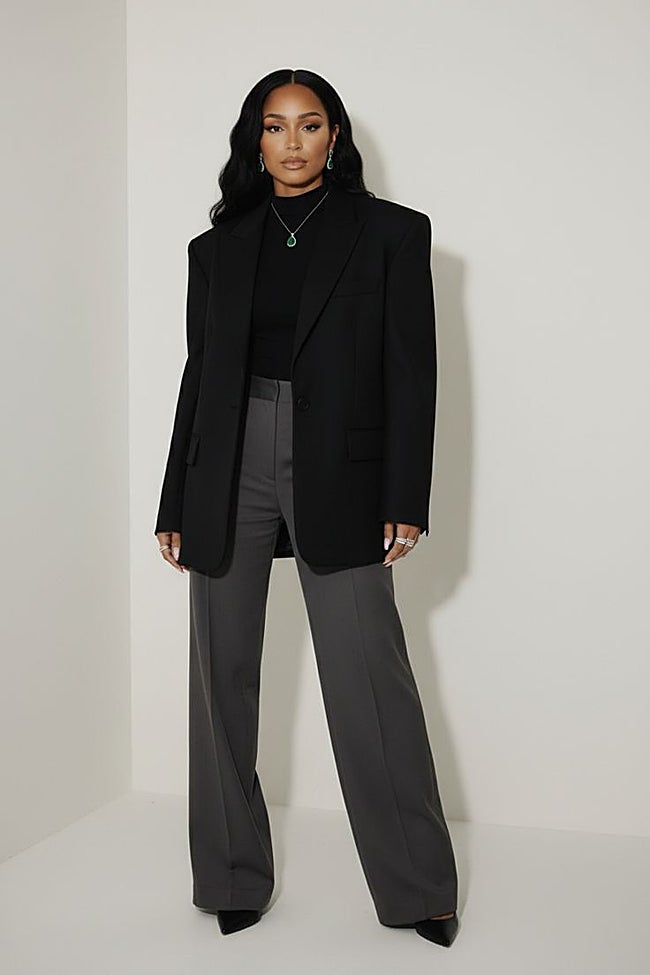 Cuello alto y americana negra con pantalón gris.