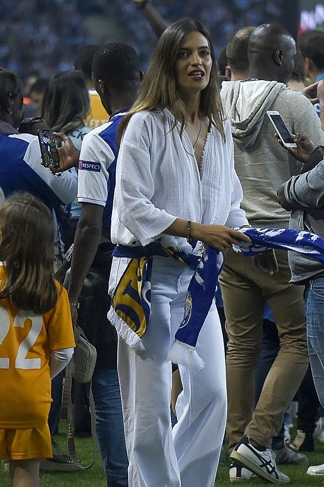 Sara Carbonero luce un look blanco compuesto por blusa y vaqueros anchos, y una bufanda del equipo.