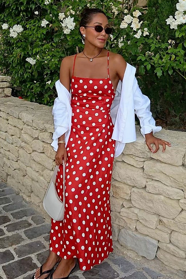 Vestido rojo de motas, bolso blanco y gafas de sol.