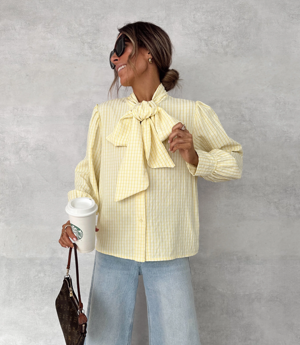 Blusa en color amarillo mantequilla y 'jeans'.