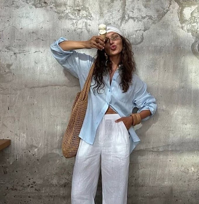 Camisa de lino azul y pantalón blanco con bolso marrón y pañuelo en la cabeza.
