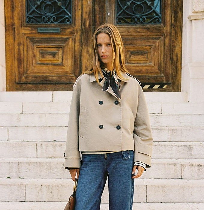 Gabardina sin cinturón clásica, pantalones vaqueros, bolso y pañuelo al cuuello.