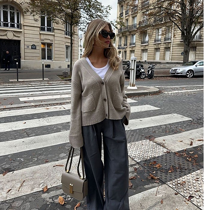 Cárdigan taupe, camiseta básica blanca, pantalones de traje grises, bolso y gafas.