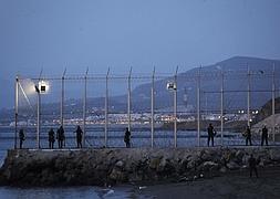 Agentes de la Policía Nacional vigilan el perímetro fronterizo de la playa del Tarajal, en Ceuta. / Efe