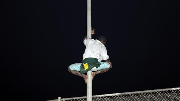 Un inmigrante de origen subsahariano intenta saltar la valla para entrar en Melilla. 