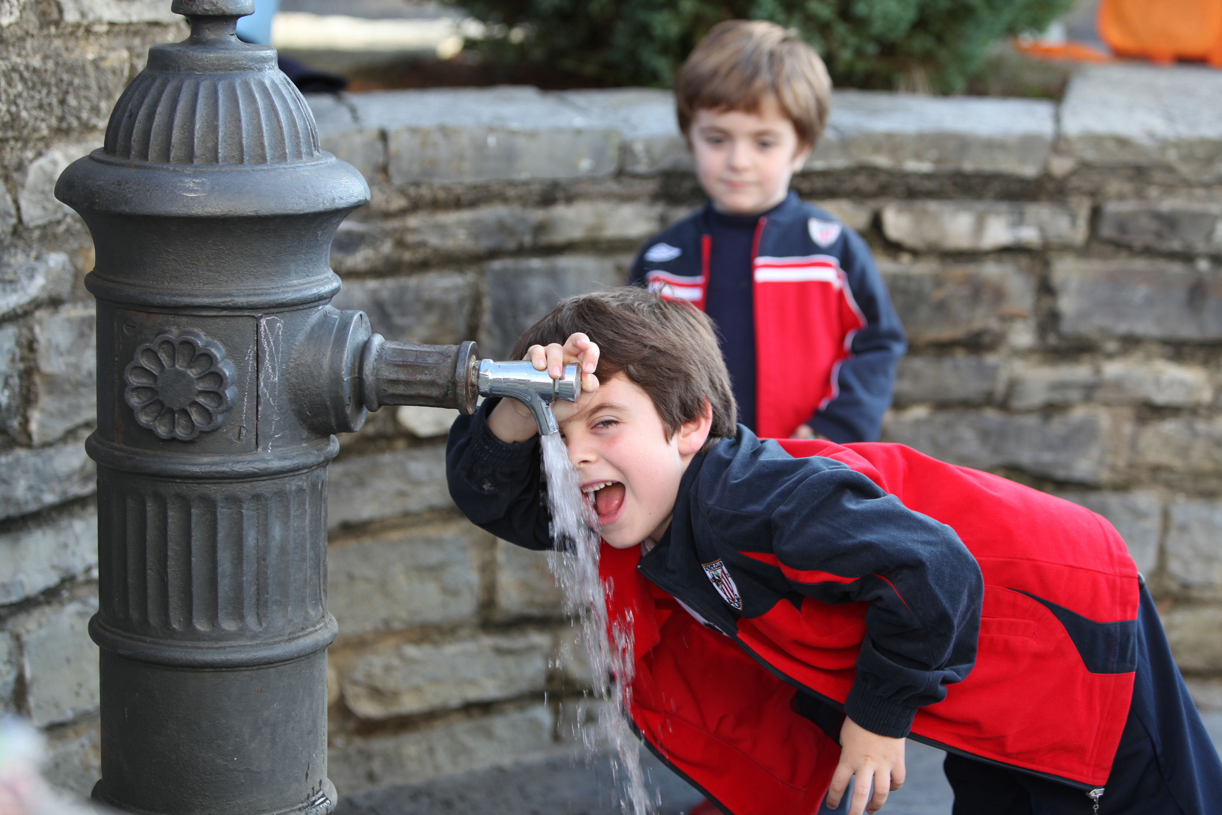 Niños bebiendo agua de una fuente.