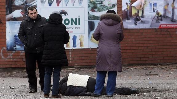 Tres personas junto a un cadáver en Mariúpol. 