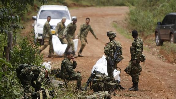 Un grupo de soldados observa a algunos compañeros transportar los restos de algunos de los 11 soldados muertos tras un ataque de las FARC.