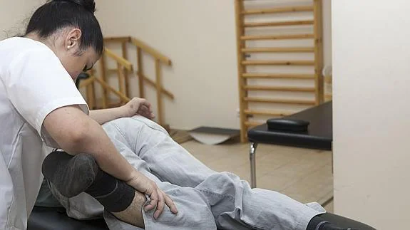 Una fisioterapeuta realiza sesiones de rehabilitación a un paciente de esclerosis múltiple.