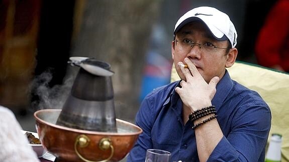 Un hombre fuma en la terraza de un restaurante en Pekín.